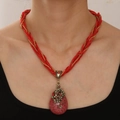 Nahaufnahme eines böhmischen roten Tropfenanhängers mit floralem Metalldetail - Rot