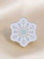 Détail macro d'une broche flocon en émail avec accents bleus sur base dorée - Flocon de neige
