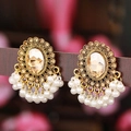 Boucles d'oreilles vintage dorées avec ambre et franges de perles sur un support sombre - Champagne