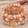 Close-up of peach beaded multilayer bracelet featuring a tree of life heart pendant - Pink