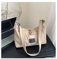 Detail shot of beige nylon tote bag with brand logo on a desk with a laptop - Khaki