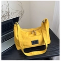 Detail of yellow nylon tote bag featuring front pocket with label and adjustable strap - Yellow