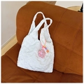 White tote bag with 3D floral texture and pink flower charm on a corduroy sofa - White with Pendant