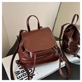 Détail du mini sac à dos en cuir brillant brun-rouge avec logo embossé et texture lisse - Marron