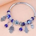 Minimalistisches Evil Eye und Hamsa Hand Charm Perlenarmband auf pfirsichfarbenem Grund - Blau