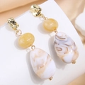 Dettaglio macro di orecchini pendenti oro rétro con perle gialle e gocce marmorizzate - Bianco