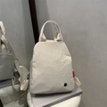 Minimalistischer cremefarbener Nylon-Rucksack mit rotem Etikett und Tragegriff - Beige