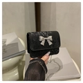 Detalle de mini bolso negro con textura de serpiente y hebilla de lazo plateado - Negro