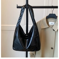 Close-up of black patent leather shoulder bag with glossy finish and rectangular patch - Black