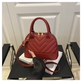 Detail der roten Stepptasche mit V-Nähten und goldenem Reißverschluss auf Stuhl - Rot