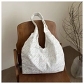 Detail of floral eyelet embroidery on white hobo shoulder bag over a wooden chair - Flower Style