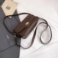 Detailed view of deep brown leather crossbody bag with elegant gold oval twist lock - Brown