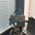 Chic black handbag with sequin flap detail and gold metal buckle shown in hand - Black