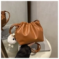 Detalle de bolso tipo cubo plisado marrón con colgante de peluche y logotipo dorado - Con Colgante / Marrón