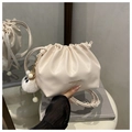 Detalle del bolso tipo saco crema con logotipo dorado y un colgante de peluche suave - Con Colgante / Blanco