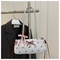 Détail du sac baguette bleu clair avec motifs nœuds rouges et pendentif cœur argenté - Bleu