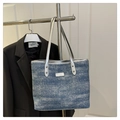 Dettaglio borsa tote in denim blu con placca logo e tracolle argentate in ecopelle - Blu