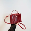 Red crocodile texture handbag with silver V buckle and adjustable strap in front view - Red