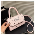 Close-up of pink mini bag with black bow patterns and silver metallic bow buckle clasp - Pink