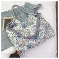 Detail of floral tote bag with purple plaid straps and braided rope handles on denim - Blue