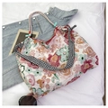 Close-up of floral canvas tote with red trim and stylish black and white checkered straps - Pink