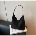 Dettaglio borsa hobo in camoscio nero con strass scintillanti sopra un libro bianco - Nero