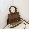 Brown leather handbag with unique circular handle and gold logo in a stylish setting - Coffee