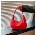 Close-up of red woven leather texture on a crescent shoulder bag in intrecciato style - Red
