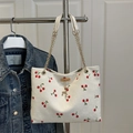 White corduroy tote bag with cherry print and golden chain straps in a 45-degree view - White