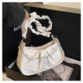 Detail einer cremefarbenen Faltenhandtasche mit Perlen und Kette in einer schwarzen Box - Weiß