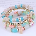 Detail of bohemian layered beaded bracelet with a golden owl charm and pastel resin beads - Colorful