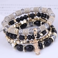 Macro shot of owl charm bracelet with patterned beads and layered metallic accents - Black