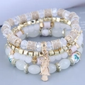 Detail of layered beaded bracelet with golden owl charm and white translucent beads - White