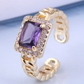 Makroaufnahme eines vergoldeten offenen Rings mit lila Zirkon und Kettenarmband - Lila (1#)