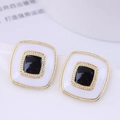 Macro detail of geometric square earrings with black and white enamel in gold finish - Square Enamel / Black With White Stone