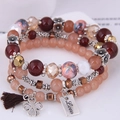 Vista macro del bracciale a strati con ciondolo a quadrifoglio e piastrina Love - Stile 4-Pesca Oro Marrone