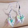 Detailed close-up of heart-shaped crystal earrings with AB aurora coating on silver hooks - White