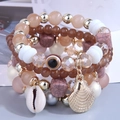 Dettaglio macro di bracciali multistrato boho con ciondoli a conchiglia e malocchio - Toni della Terra (1)