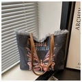 Detail of canvas tote bag with butterfly print, fringe trim, and brown handles - Black