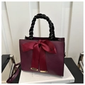 Close-up of wine red bridal handbag featuring a large satin bow and woven handle - Burgundy