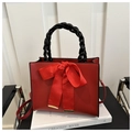 Detail of red bridal handbag with large bow, black woven handle and gold accents - Red