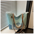Detalle del bolso tote de lona con bordes deshilachados y correas de cuero marrón - Verde