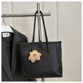 Detailed view of a black leather tote bag with a star charm on a metal stand - With Charm / Black