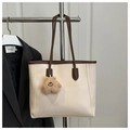 Detail of beige tote bag with brown trim and plush bear charm on a suit jacket - With Charm / White