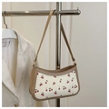 Close-up of cherry pattern print and apricot leather trim on a chic crescent bag - Khaki