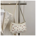 Detailed close-up of cream underarm bag featuring vibrant red cherry print and slender strap - White