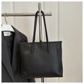 Detail view of a black minimalist tote bag with vertical stitching on a sleek metal rack - No Pendant / Black