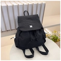 Detail view of black and white checkered drawstring backpack with puzzle piece buckle on table - Black Check