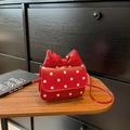 Red polka dot mini crossbody bag with a large bow detail for girls on a wooden desk - Red