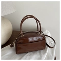 Detail of dark brown glossy Boston bag with golden zippers and a detachable shoulder strap - Brown